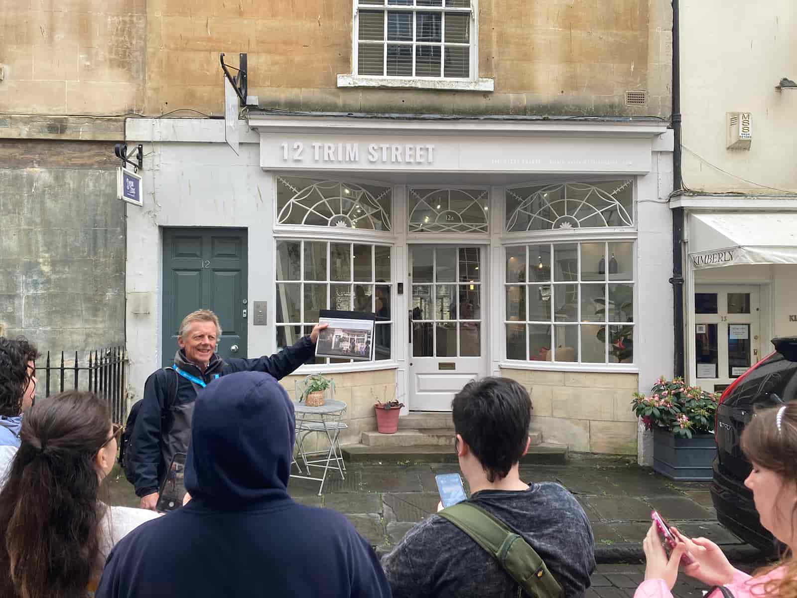 Tour guide talking to UNT students in front of a white storefront. 