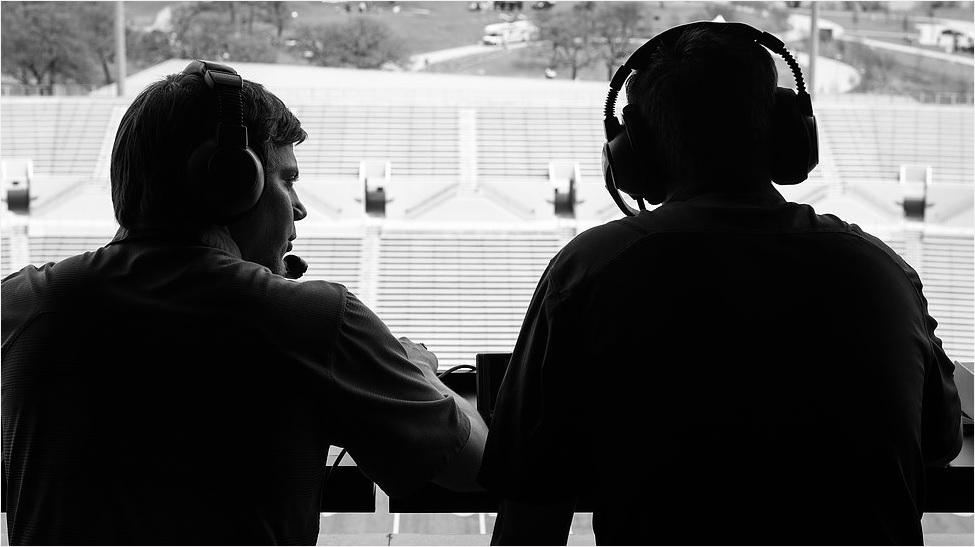 radio sports casters in silhouette. field in the background